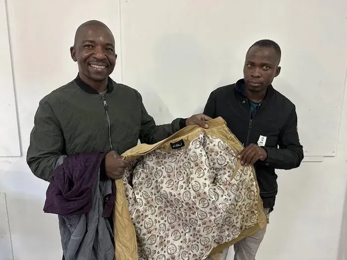 Two people proudly displaying quality clothing from a Khanya bale